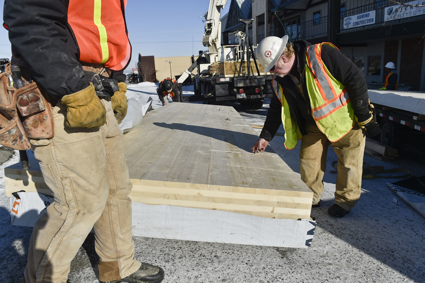 A construction worker inspects the cross-laminated timber before installing it